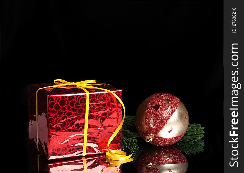 Gift,Christmas ball on the branch of a tree on a black background with reflection