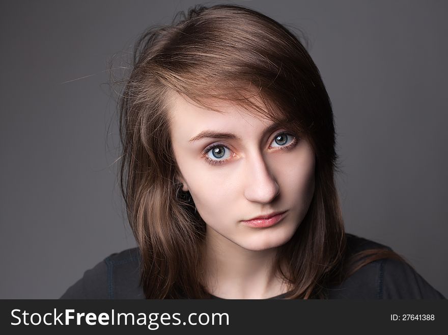 Closeup portrait of a lovely young female model looking confidently against grey background. Closeup portrait of a lovely young female model looking confidently against grey background