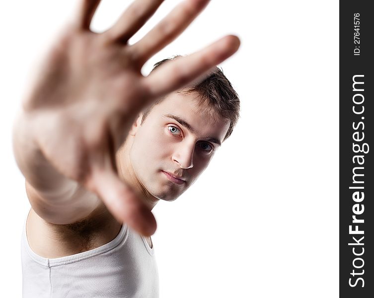 Portrait of a young man looking out from under raised hand on a light background