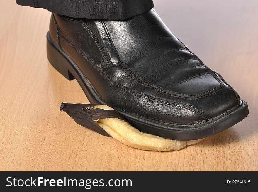 Closeup of man's black shoe stepping on over ripe banana. Closeup of man's black shoe stepping on over ripe banana