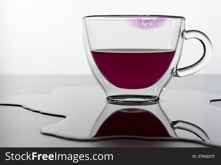 Empty glass and lipstick print and red liquid isolated on white background