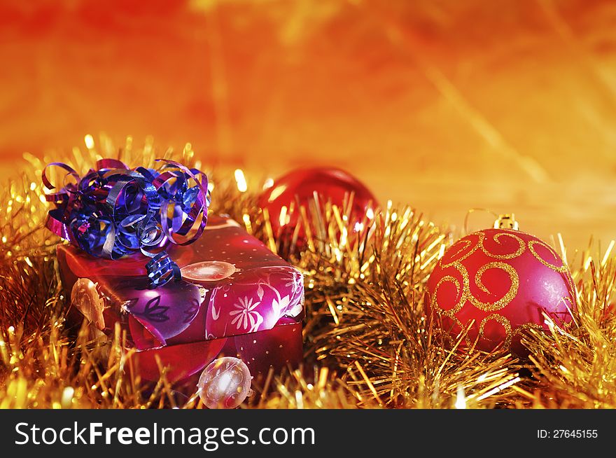 Christmas present and baubles against a blurred gold background. Christmas present and baubles against a blurred gold background