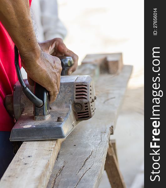 Carpenter working with electric planer in his workshop, close up on the tool with hands