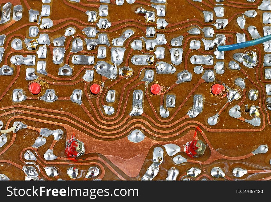 Vintage circuit board surface with tin soldering closeup technological background