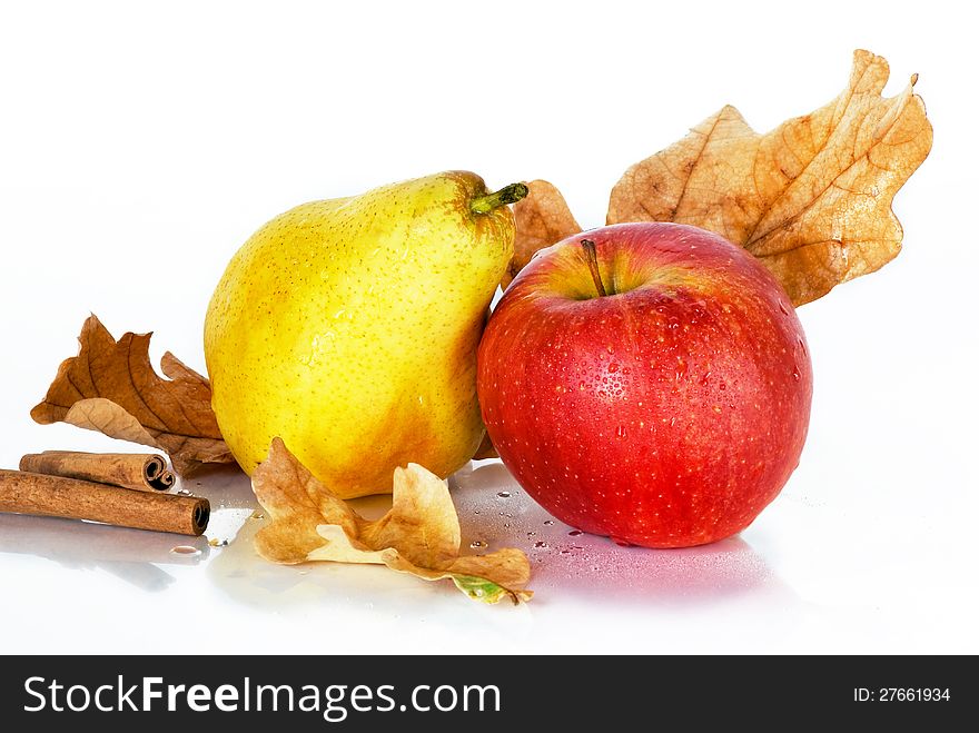 Ripe apple and pear with oak leaves and cinnamon on a white background. Ripe apple and pear with oak leaves and cinnamon on a white background