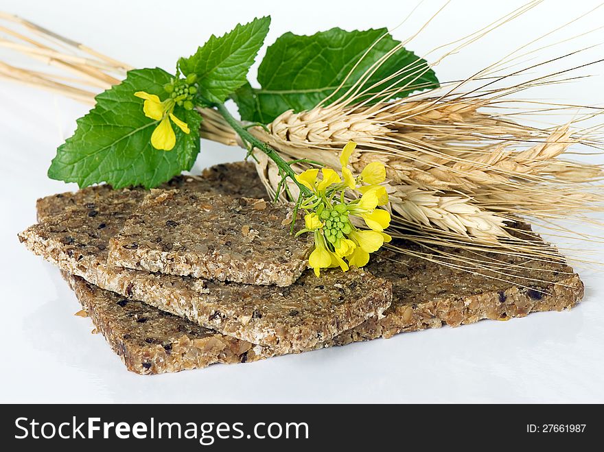 Whole wheat bread with ears of wheat and winter cress on a white background. Whole wheat bread with ears of wheat and winter cress on a white background