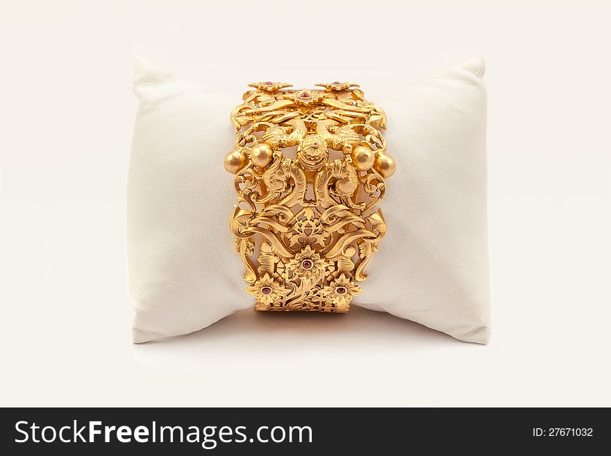 Pure Gold bracelet having itself craft of gold looking historic over white background with soft cushion. Pure Gold bracelet having itself craft of gold looking historic over white background with soft cushion