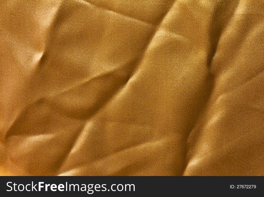 Surface has a wrinkled golden cloth and reflection of sunlight. Surface has a wrinkled golden cloth and reflection of sunlight.