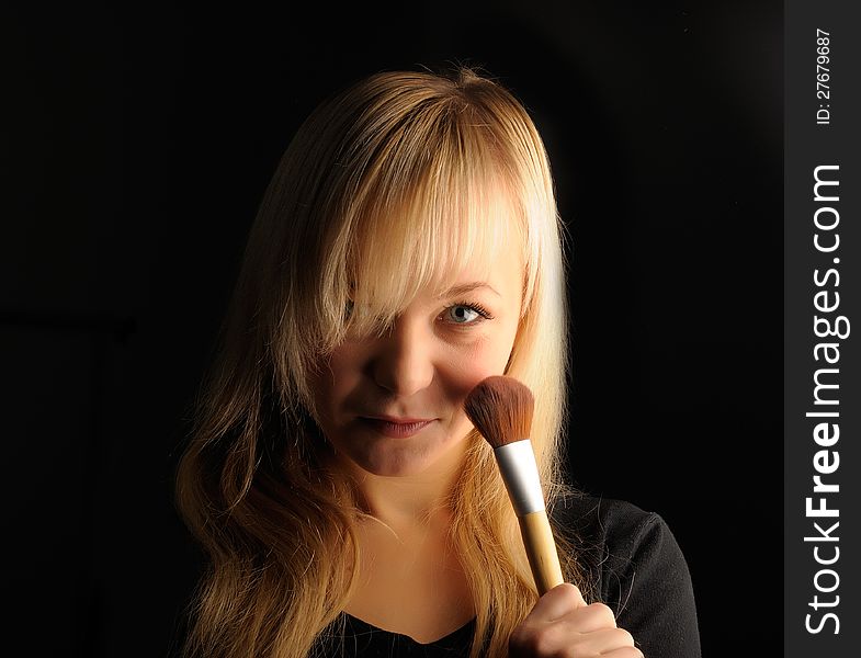 Young blond hair woman portrait  with make-up brush on dark background