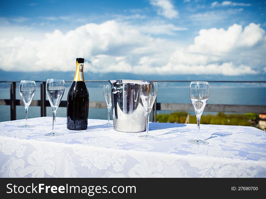 Table with glasses and bottle of shampagne  on a background of a Garda lake. Table with glasses and bottle of shampagne  on a background of a Garda lake