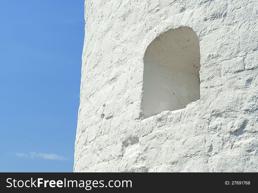 A fragment of the fortress wall with loopholes against the blue sky