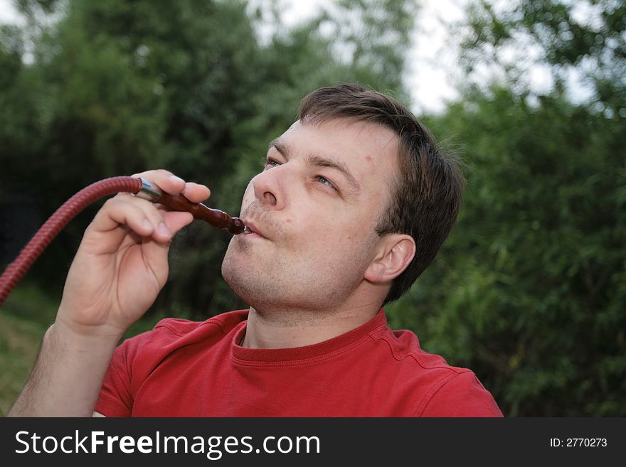 Man in red smokes a hookah outdoor