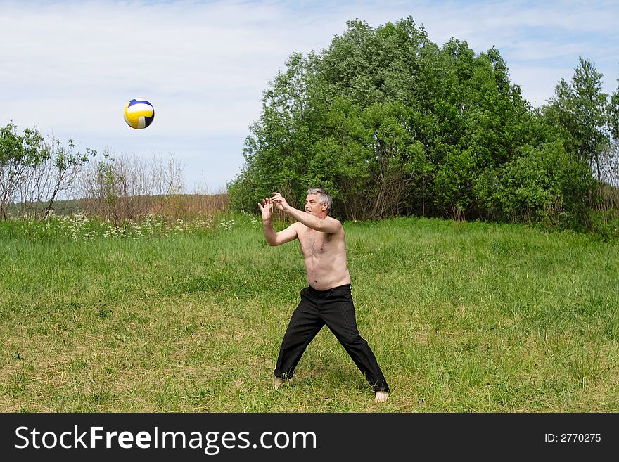 The man plays with a ball outdoor in the summer. The man plays with a ball outdoor in the summer