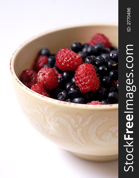 Bowl of fresh forest raspberry and blueberry, focus on raspberries