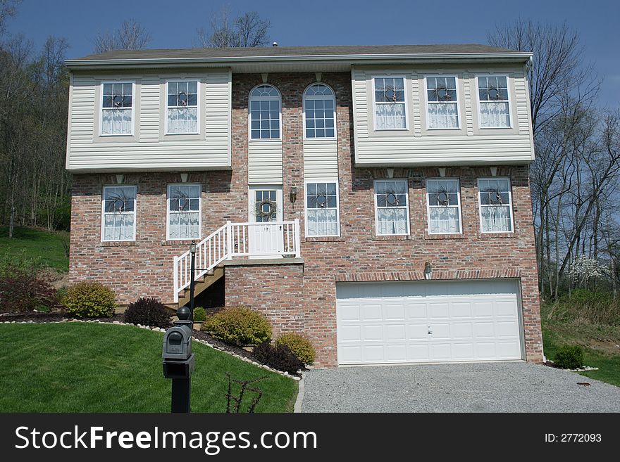 Two-story farm style home with porch and railing in the suburbs. Two-story farm style home with porch and railing in the suburbs.