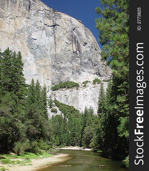 A stream running in front of a four thousand foot glacier carved white granite cliff. A stream running in front of a four thousand foot glacier carved white granite cliff.