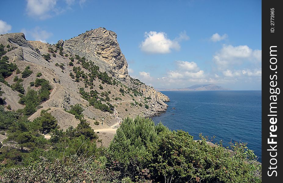 Big rocky mountains, sea and sky with white clouds. Big rocky mountains, sea and sky with white clouds