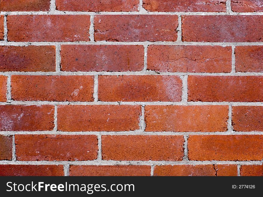 An old red brick wall, some cracks, with grey white mortar close up