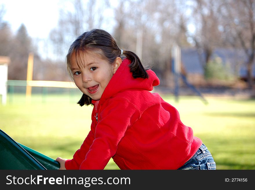 Four year old girl climbing up a slide at the playground. Four year old girl climbing up a slide at the playground.