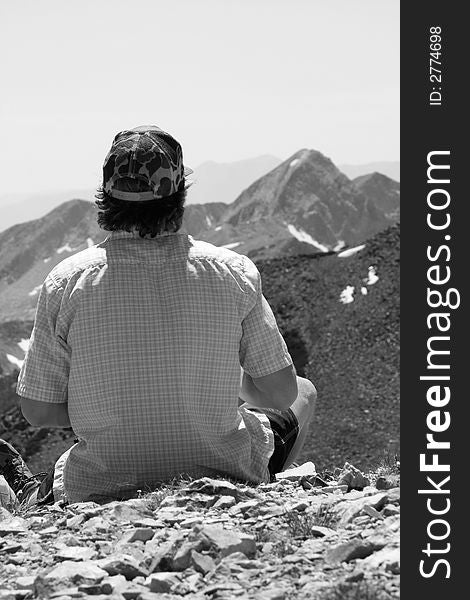 A man stops for a break and admires the view in black and white. A man stops for a break and admires the view in black and white
