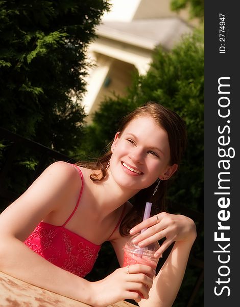 Beautiful, happy teen in formal wear outside with a fruity drink. Beautiful, happy teen in formal wear outside with a fruity drink