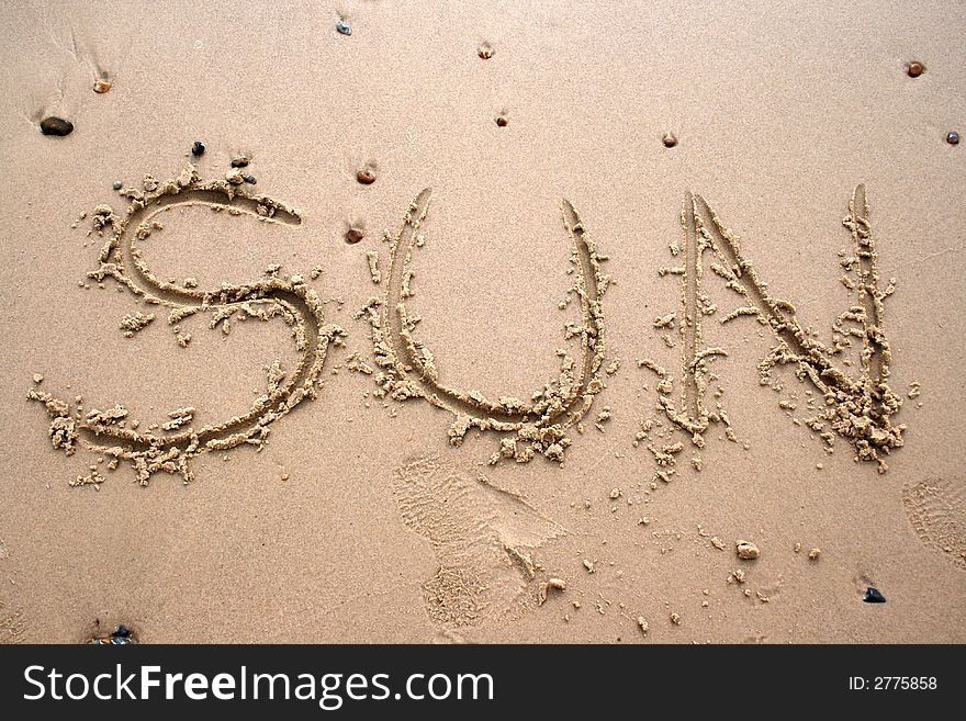 The word Sun written in sand next to the shore. The word Sun written in sand next to the shore