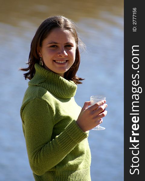 Young woman standing next to a river, enjoying a glass of wine. Young woman standing next to a river, enjoying a glass of wine.