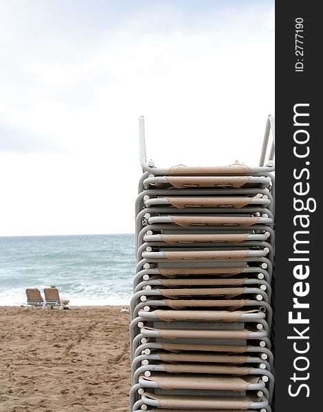 A large stack of beach chairs on the beach. A large stack of beach chairs on the beach