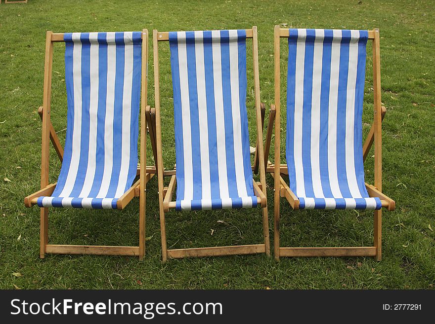 Three blue and white stripped empty deckchairs in a park london england uk taken in july 2007. Three blue and white stripped empty deckchairs in a park london england uk taken in july 2007