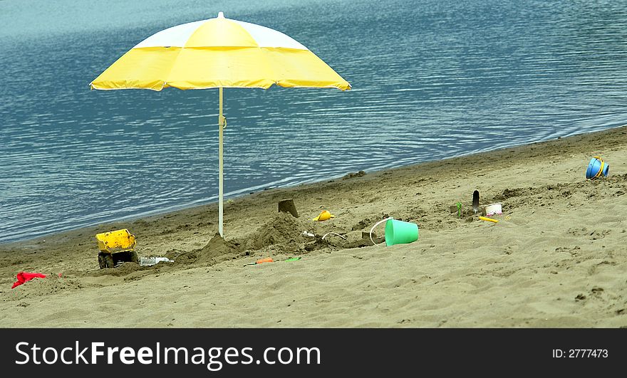 Yellow beach umbrella with scattered sand toys