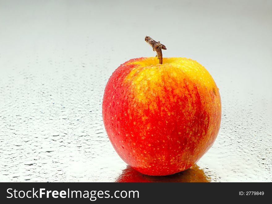 Red apple on  surface of  water covered with drops