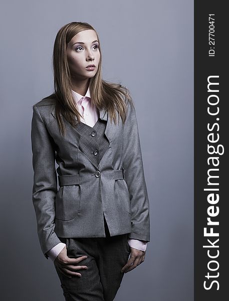 Trendy woman posing in grey costume. Studio shot