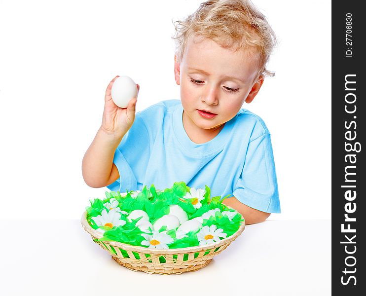 Boy sitting at a table covered with a basket of eggs. Boy sitting at a table covered with a basket of eggs