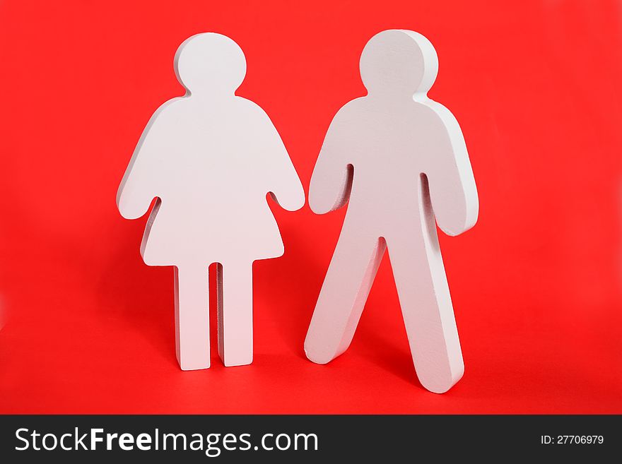 Male and female wooden figures on a red background. Male and female wooden figures on a red background