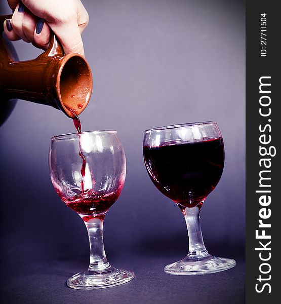 Pouring wine from an ancient pitcher dark background