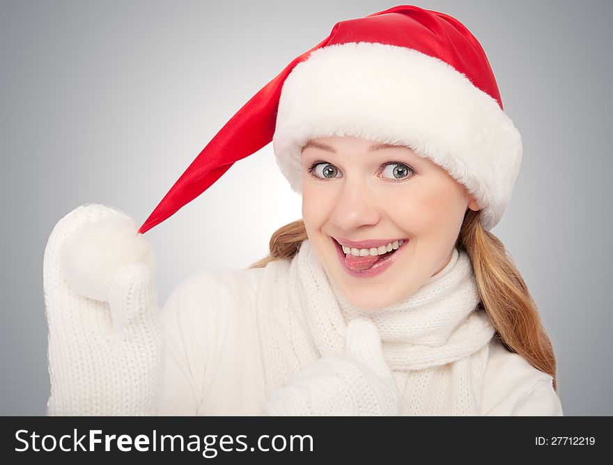 Happy funny girl in a Christmas hat show tongue on gray background