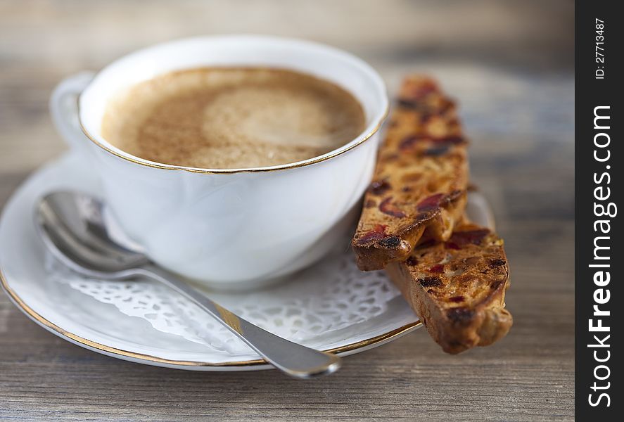 A cup of coffee and biscotti on a wooden table. A cup of coffee and biscotti on a wooden table