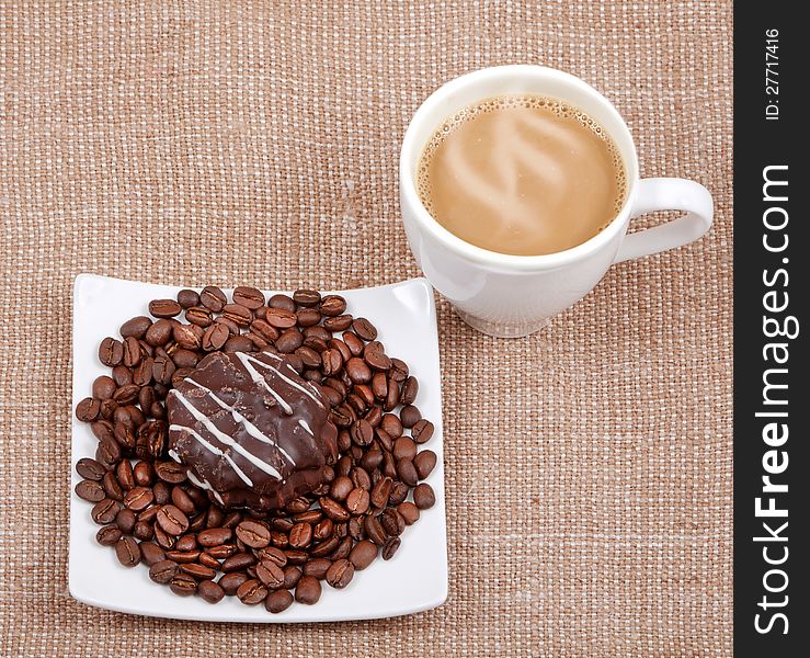 Coffee with milk on sacking,a saucer with a coffee bean and chocolate biscuits