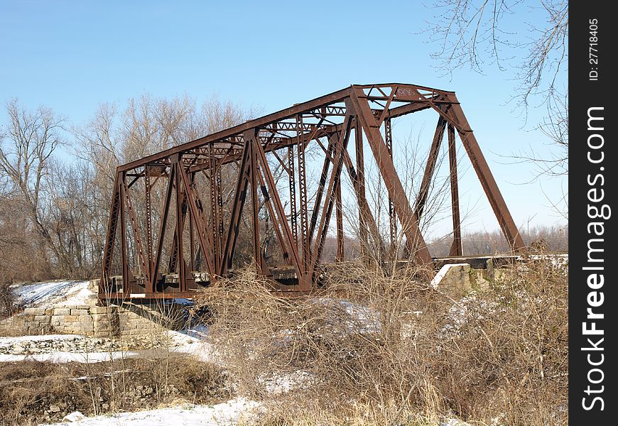 A rusted railway bridge in a snowy winter scene