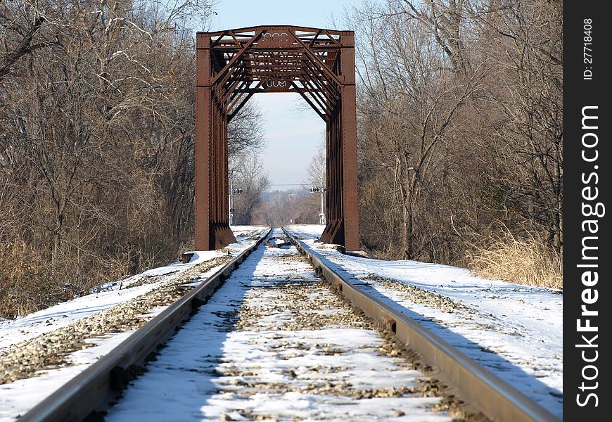 A rusted railway bridge in a snowy winter scene