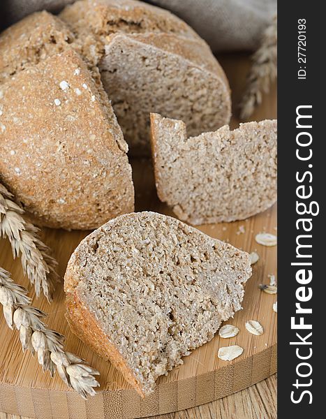 Bread with oat flakes chopped to pieces on a wooden board, vertical. Bread with oat flakes chopped to pieces on a wooden board, vertical