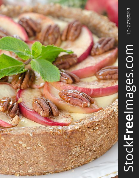 Cheesecake with apples and caramelized pecans closeup, selective focus