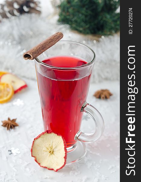 Mulled wine with cinnamon and spices in a glass glass, tinsel and Christmas tree in the background. Mulled wine with cinnamon and spices in a glass glass, tinsel and Christmas tree in the background