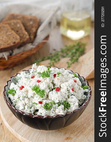Cottage cheese pate with herbs and chili pepper in a ceramic bowl on a wooden board. Cottage cheese pate with herbs and chili pepper in a ceramic bowl on a wooden board