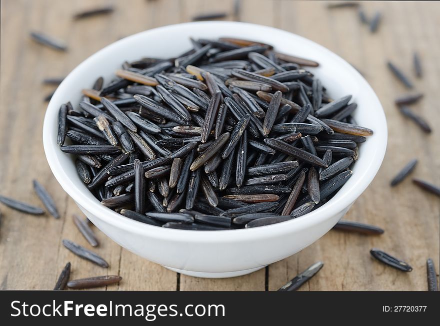 Wild rice in a bowl on wooden table closeup. Wild rice in a bowl on wooden table closeup