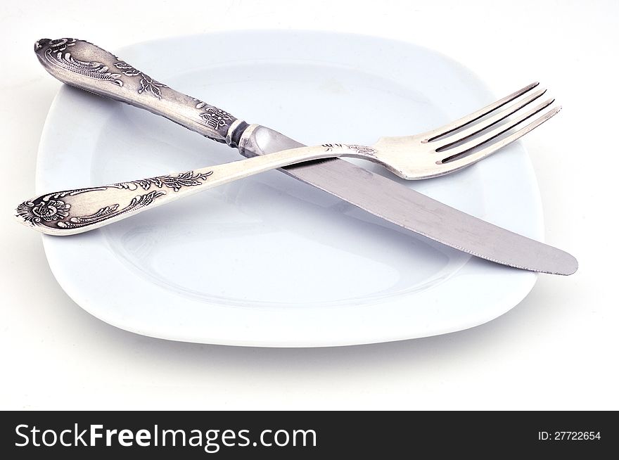 Knife and fork are on a white plate against a white background
