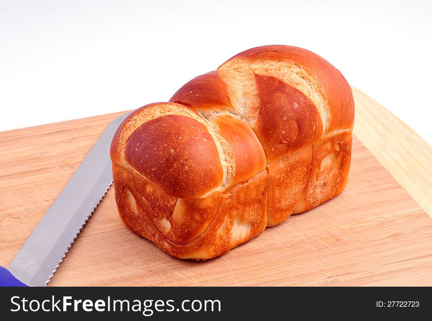 Loaf of bread is dark gray on a wooden board next to the knife. Loaf of bread is dark gray on a wooden board next to the knife