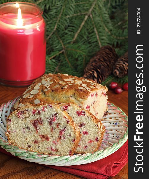 Sliced cranberry bread on a plate with candle burning in background. Sliced cranberry bread on a plate with candle burning in background