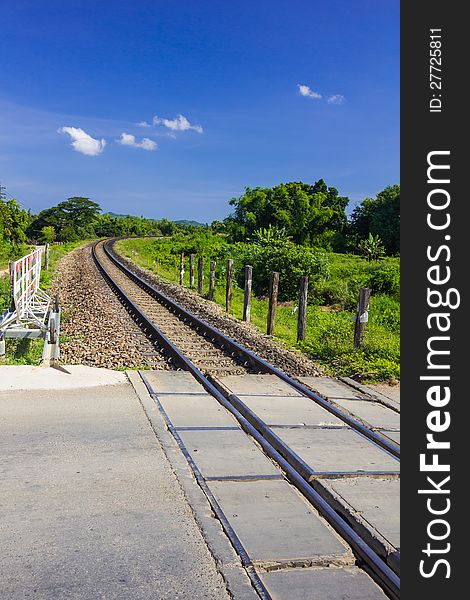 Curve railway track cross the road with mountain background