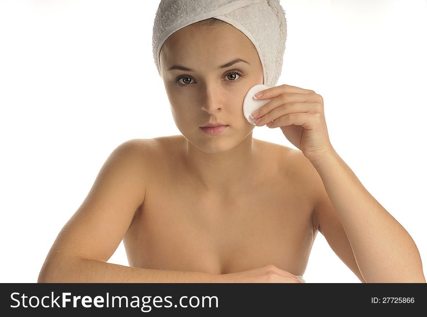 Close-up portrait of young beautiful woman with cotton swab cleaning her face